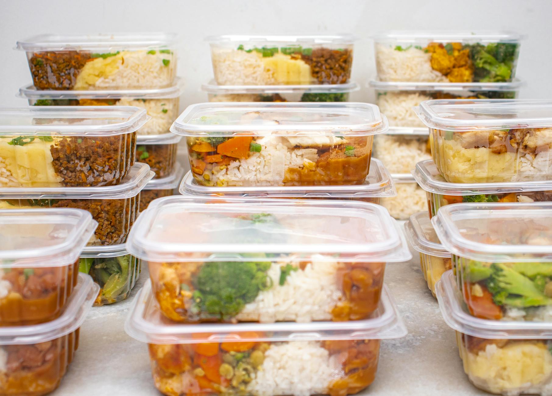 bright overhead shot of a kitchen table with neatly labeled meal-prep containers, seasonal vegetables, and a handwritten weekly meal plan