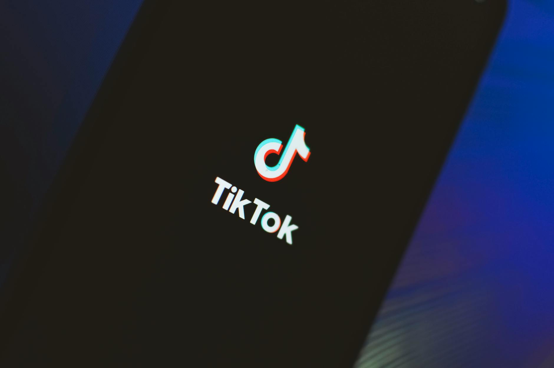 close-up of a smartphone showing a TikTok “de-influencing” video, with a shopping cart icon crossed out and alternative product screenshots visible