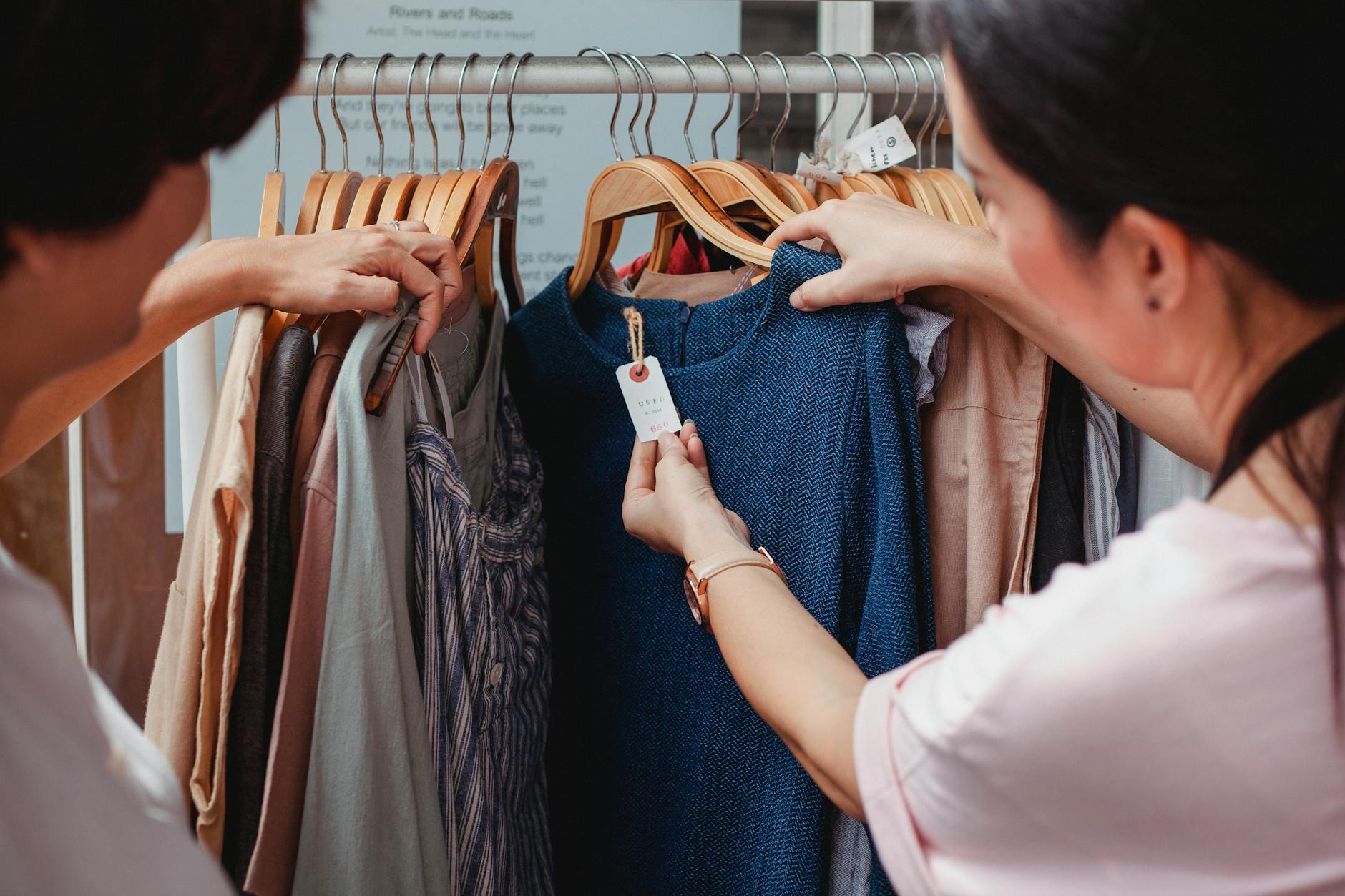 colorful vintage clothing racks inside a bustling thrift store with handwritten price tags and shoppers browsing