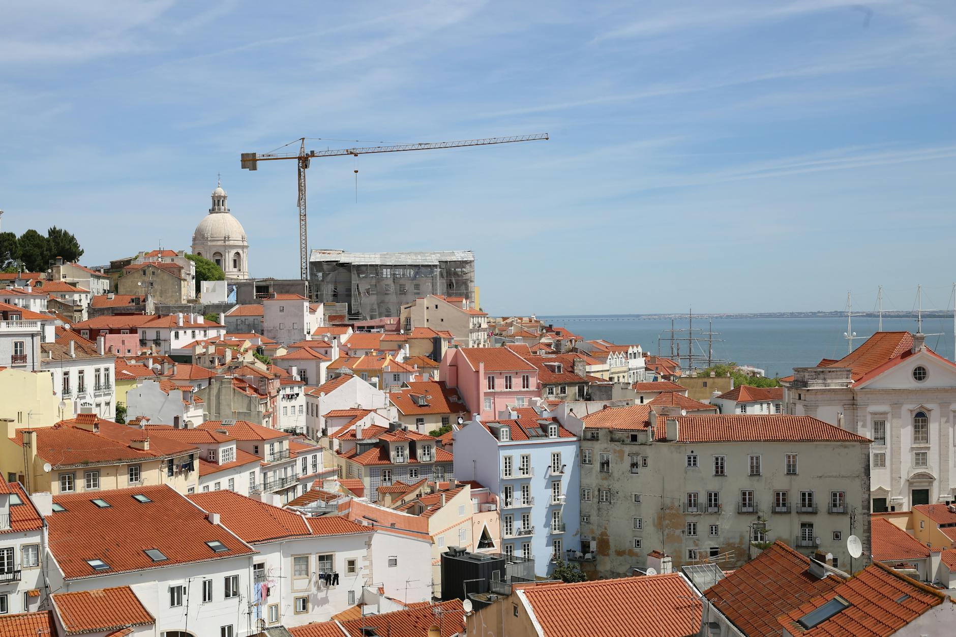 Most Affordable Travel Destinations to Visit in 2026 3 sunlit Lisbon viewpoint overlooking red rooftops and a river, with a traveler holding a pastel de nata
